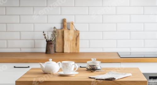 Preview: Wooden oak table with a cup of tea and a kettle in front of the kitchen with a white background.