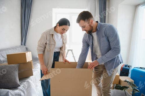 Preview: Young couple packing moving boxes for relocation