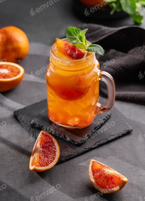 Preview: Freshly squeezed blood orange juice with mint and a slice of fruit in a jar on a dark background