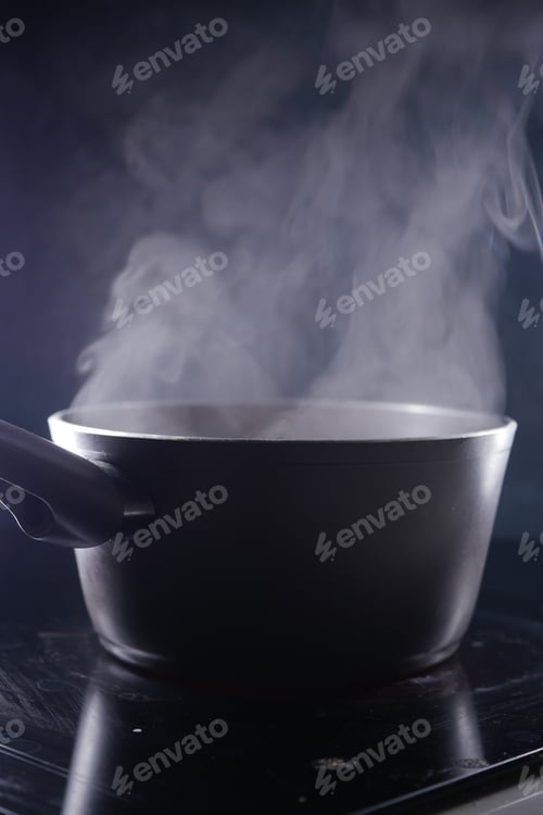 Preview: Cooking pot emits steam on a dark kitchen surface at night