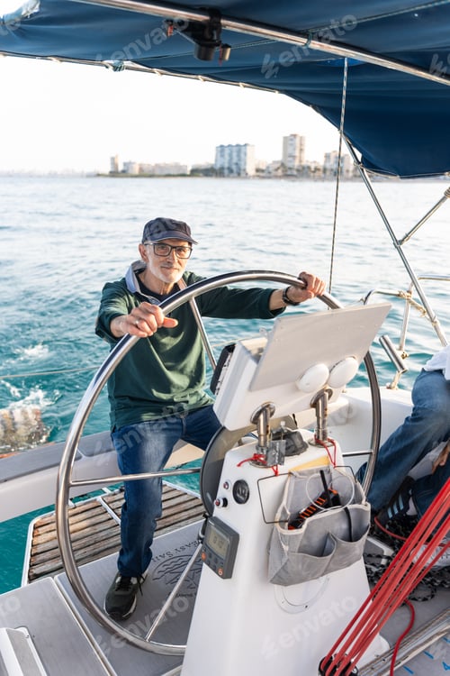 Preview: Senior man steering sailboat on sunny day