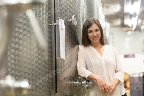 Preview: Portrait of young woman, leaning against fermentation tank in wine cellar