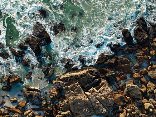 Preview: rocks along the coast of some sort and water with waves coming
