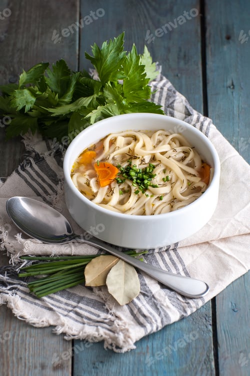 Preview: Homemade chicken soup with homemade noodles on an old wooden tab