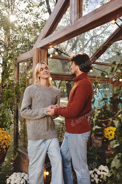 Preview: Young couple enjoying a romantic moment in a cozy greenhouse surrounded by flowers