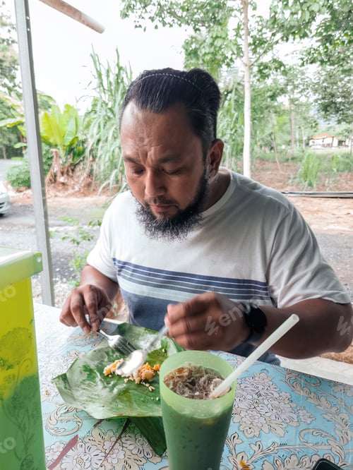 Preview: Bearded man eating nasi lemak at the local stall in the morning.