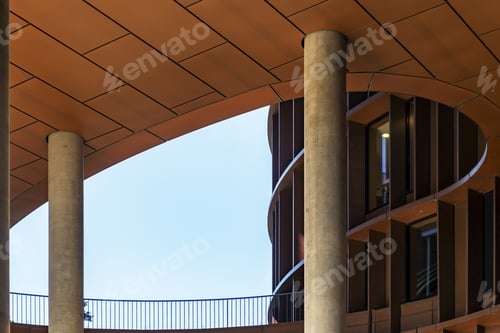 Preview: Low angle shot of a brown round-shaped modern building with curvy twists under the clear sky