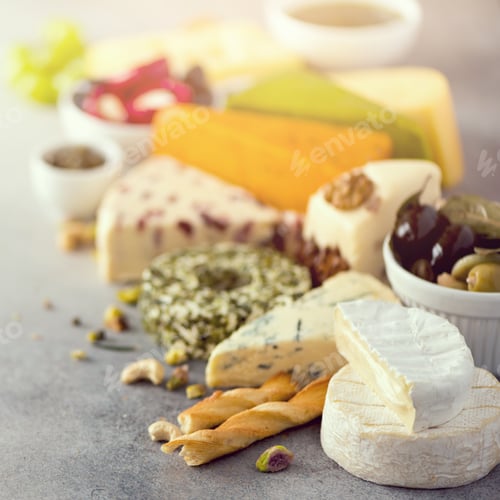 Preview: Assortment of hard, semi-soft and soft cheeses with olives, grissini bread sticks, capers, grape, on