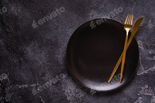 Preview: Clean empty black plate with cutlery.