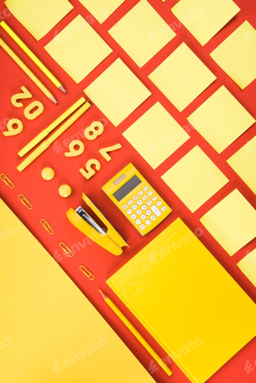 Preview: flat lay with arranged yellow schooling supplies in rows on red