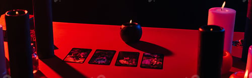 Preview: KYIV, UKRAINE - JUNE 29, 2022: red table with candles and tarot cards isolated on black, banner