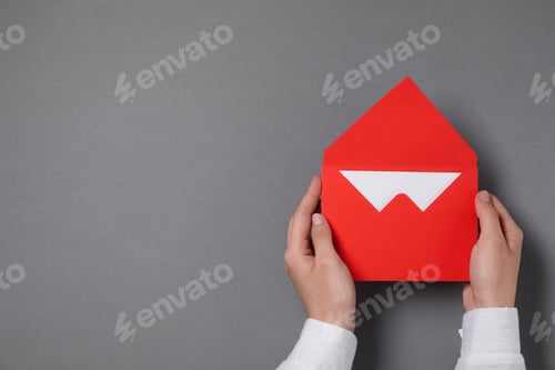 Preview: Woman holding letter envelope with card at grey table, top view. Space for text