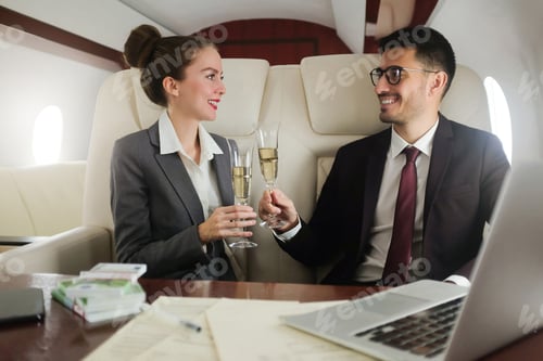 Preview: Business team travelling in private jet, dressed in suits drinking champagne to celebrate success