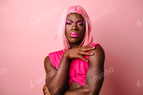 Preview: Portrait of an African transgender person posing over an isolated pink background.