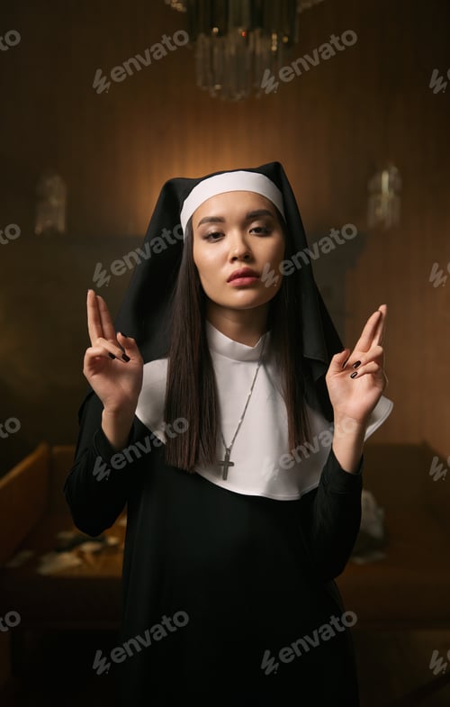Preview: Young nun with crossed fingers on hands gesturing good luck or giving support