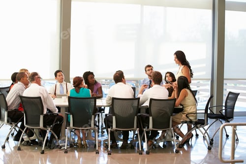 Preview: Businesswoman Addressing Meeting Around Boardroom Table