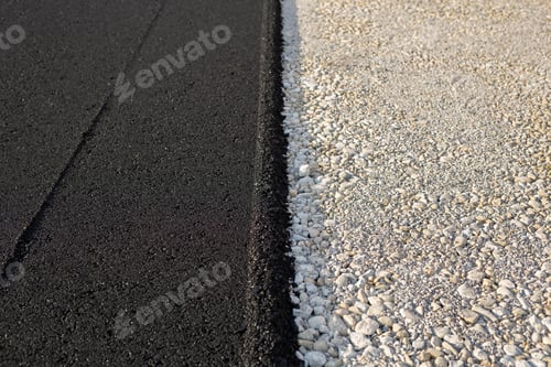 Preview: New paved road edge and curb. The texture of new asphalt and crushed stone.