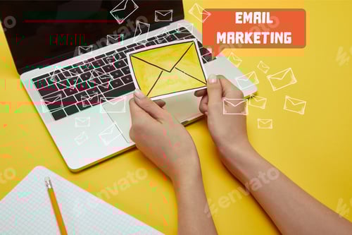 Preview: cropped image of woman holding envelope sign near laptop with"email marketing" lettering and email