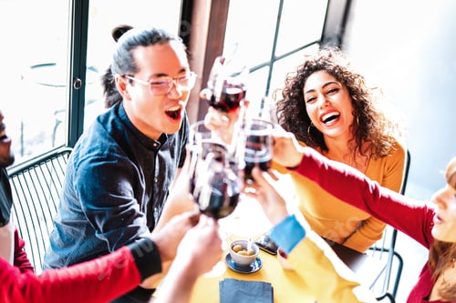 Preview: Young multiracial friends drinking and toasting red wine at dinner party