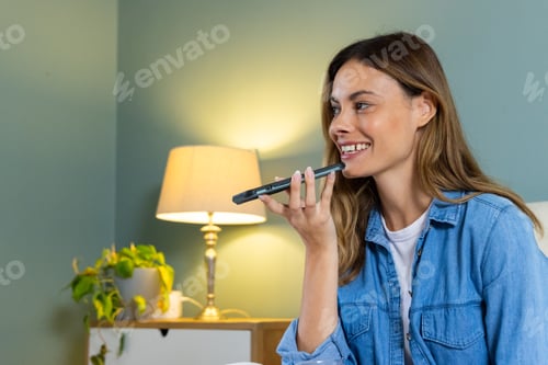 Preview: Smiling woman using smartphone voice assistant at home, relaxing on couch