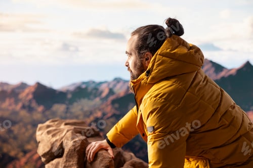 Preview: Male hiker looks out over a breathtaking mountain range from the hill top