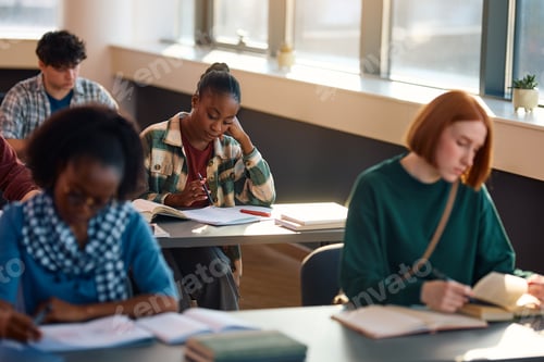 Preview: Black female student studying for upcoming exam at college classroom.