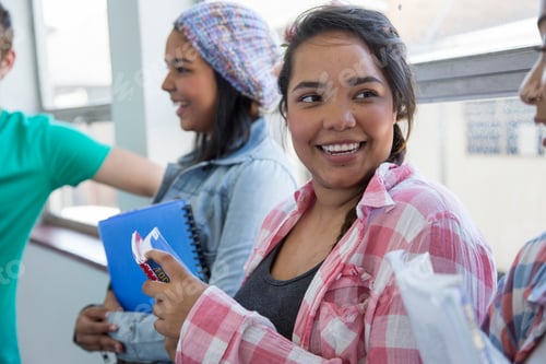 Preview: Smiling teenage girl holding books in a school setting.