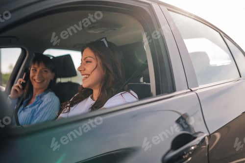 Preview: Cheerful female driver sitting in a car and driving it on city street.