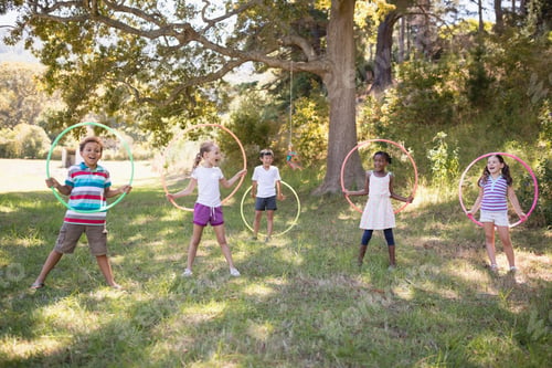 Preview: Group of cheerful friends playing with hula hoops at campsite