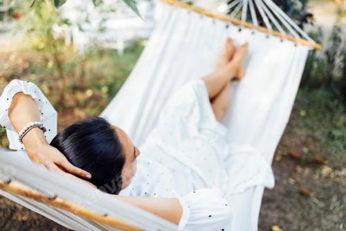 Preview: Young female brunette expecting baby in white dress resting on outdoors