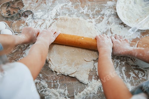 Preview: Top view of two little girl's hands that preparing knead by tool on the table