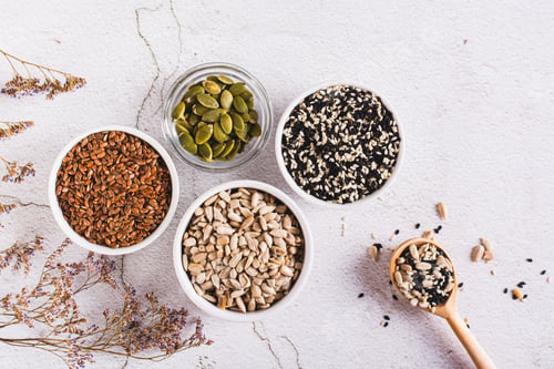 Preview: Sesame, flax, pumpkin and sunflower seeds in bowls and spoon for women's health top view
