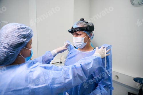 Preview: Surgical nurse helps a doctor put on a surgical gown