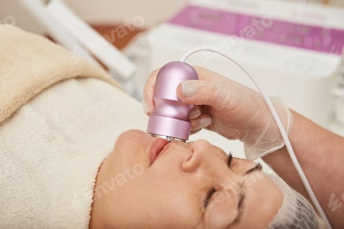 Preview: Middle-aged woman receiving facial treatment in clinic