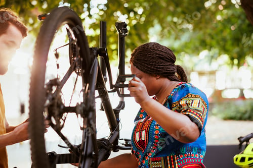 Preview: Multiracial couple repairing bicycle