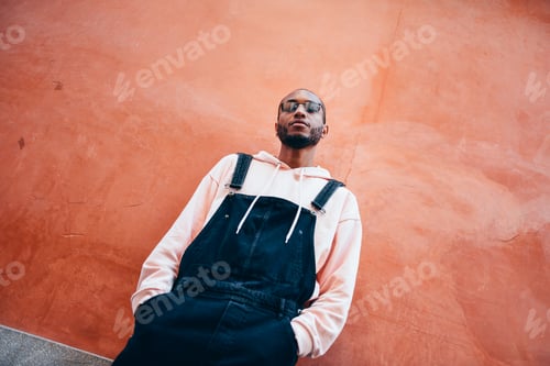Preview: Millennial African guy with bib pants outdoors