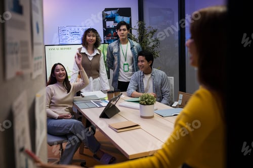 Preview: Group of young Asian professionals collaborating on a late-night project meeting in a modern office.