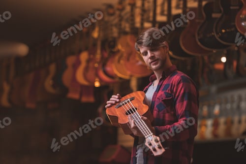 Preview: Young man with a ukulele indoors