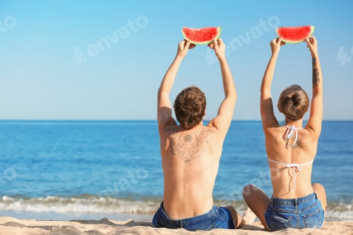 Preview: Young couple with watermelon slices on beach. Space for text