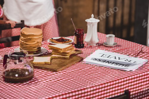 Preview: close-up view of tasty breakfast with toasts, pancakes, newspaper and coffee on table