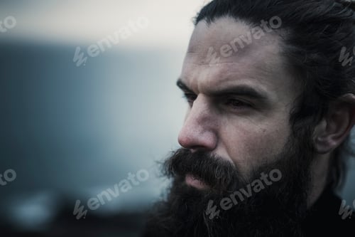 Preview: A man with full beard and moustache and black hair scrapped back from his face.
