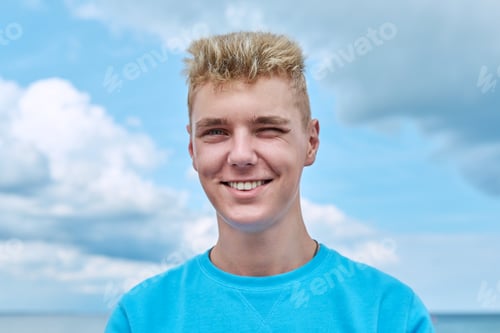 Preview: Headshot portrait of handsome smiling teenage guy, blue sky