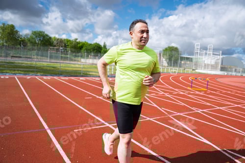 Preview: Determined man running on track, embracing fitness journey for health and well-being