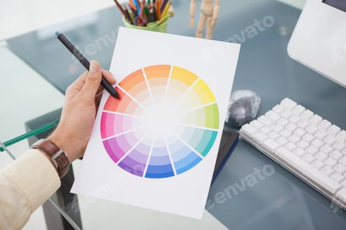 Preview: Designer working at desk using a colour wheel in his office