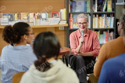 Preview: Senior Caucasian Woman Speaking into Microphone Addressing Diverse Audience