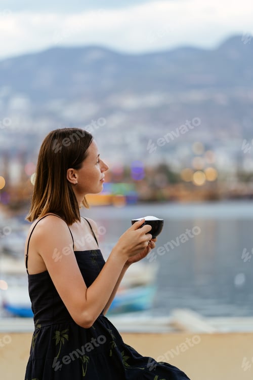 Preview: Smiling Woman enjoys a latte while sitting near the sea in the bay. Travel destination, Turkey