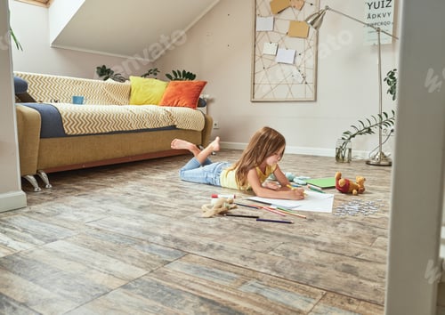 Preview: Creative child playing at home. Little caucasian girl lying on the wooden floor in the