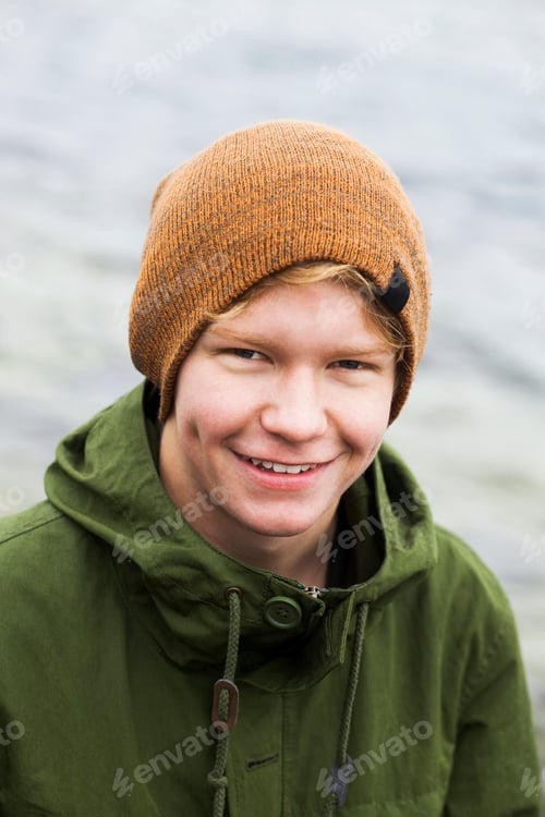 Preview: Portrait of happy teenage boy against lake