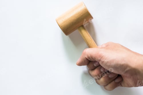 Preview: Man's hand holding a small wooden hammer (stick) White top view isolated at the studio.
