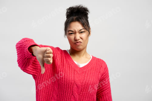Vista previa: Young woman showing thumbs down gesture expressing dislike
